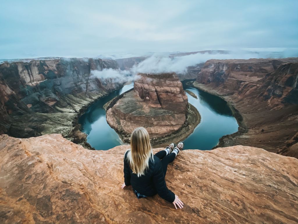 Kay sitting infront of a canyon with a river shaped like a horseshoe